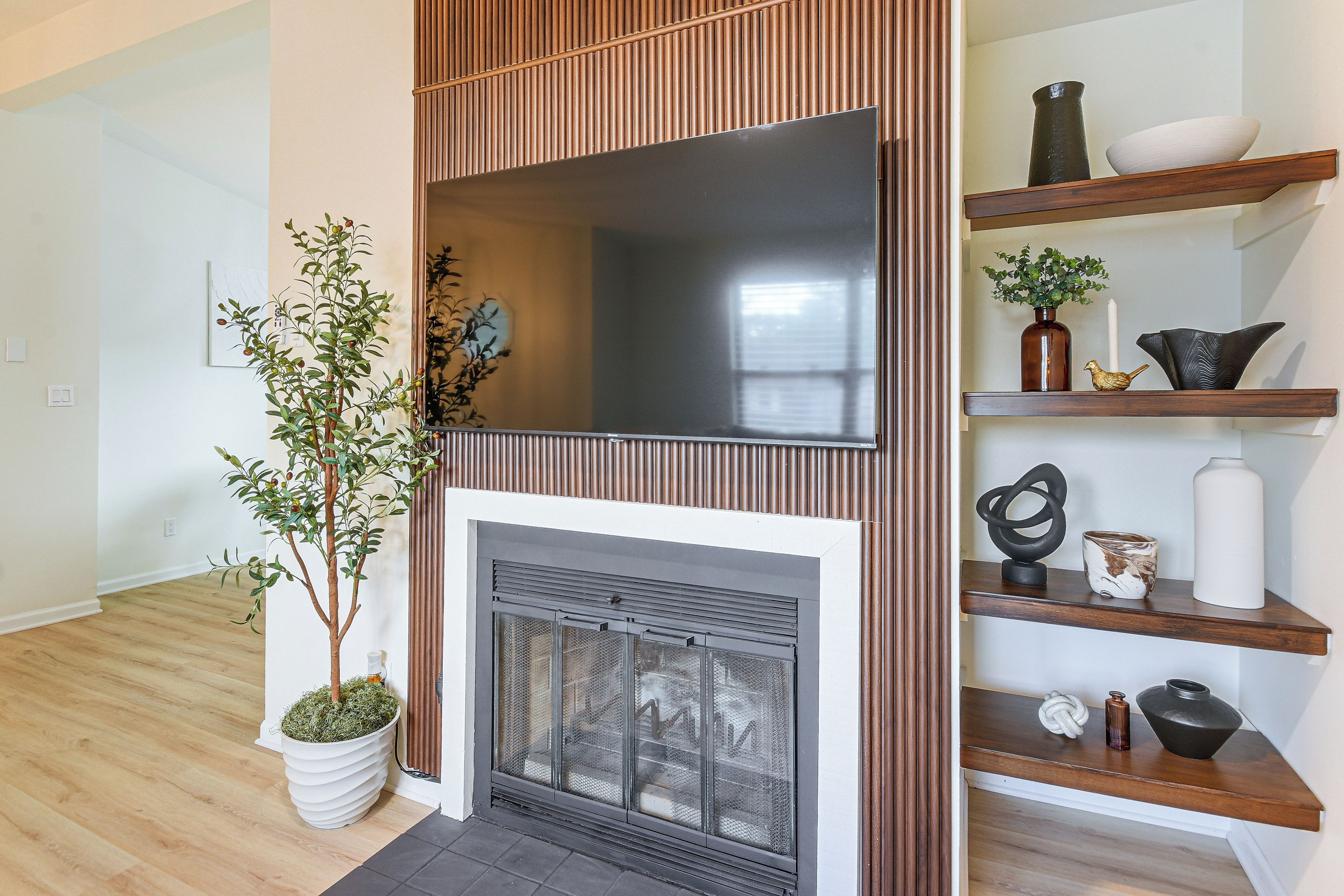 Un salón moderno con chimenea, un televisor montado encima y un revestimiento de pared de madera.