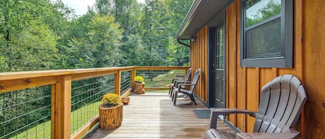 Eine Holzterrasse mit Geländer, Stühlen und Pflanzkübeln.