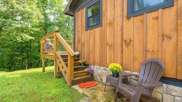 A wooden house with a stone foundation, a wooden staircase, and a chair outside.