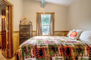 Quarto com cama, penteadeira, janela com cortinas e porta.