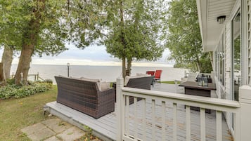 A deck with outdoor furniture overlooking a body of water.
