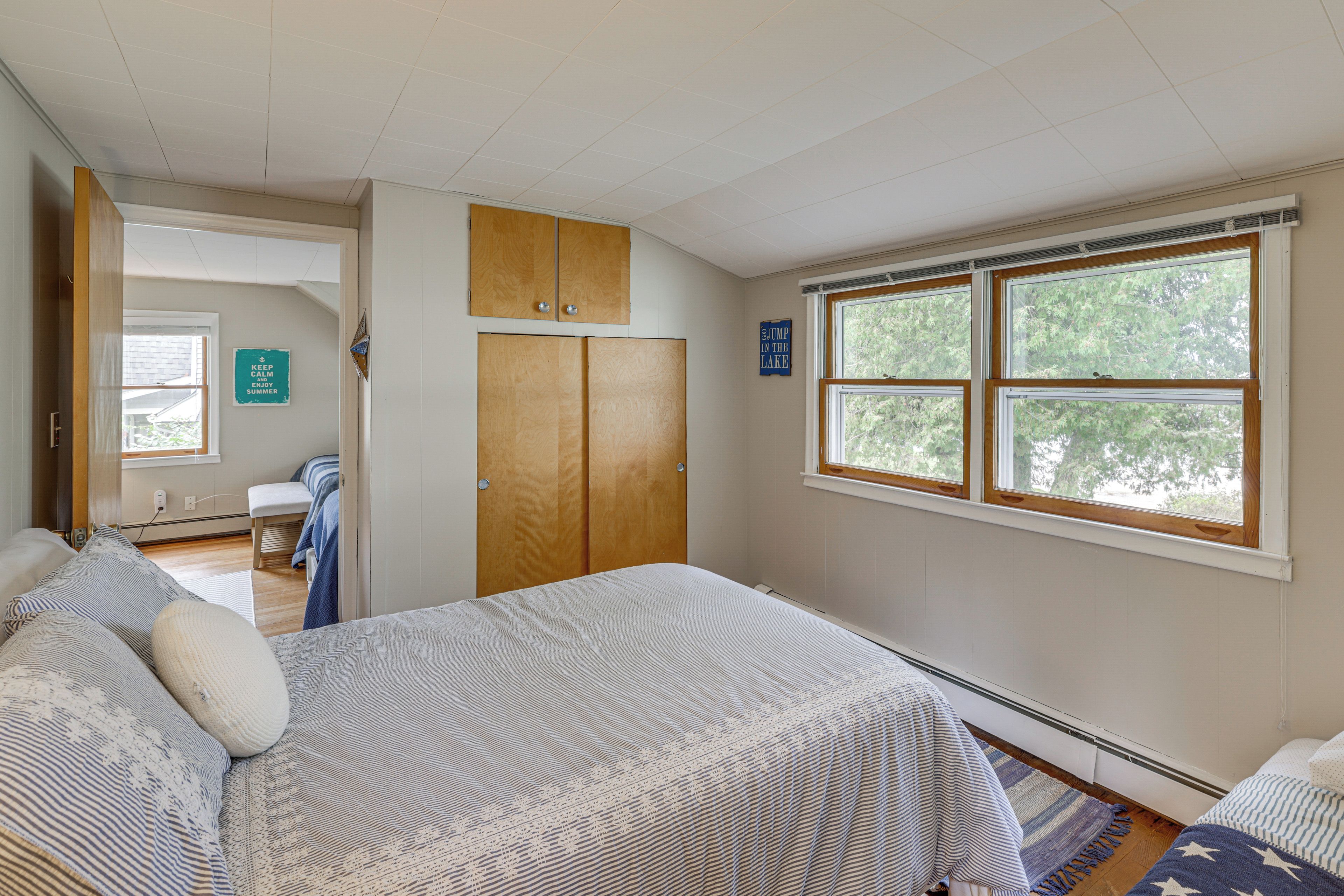 A bedroom with a bed, a window, and a door leading to another room.