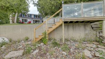 A wooden staircase leading to a glass-enclosed upper level, surrounded by a concrete wall and a rocky ground.