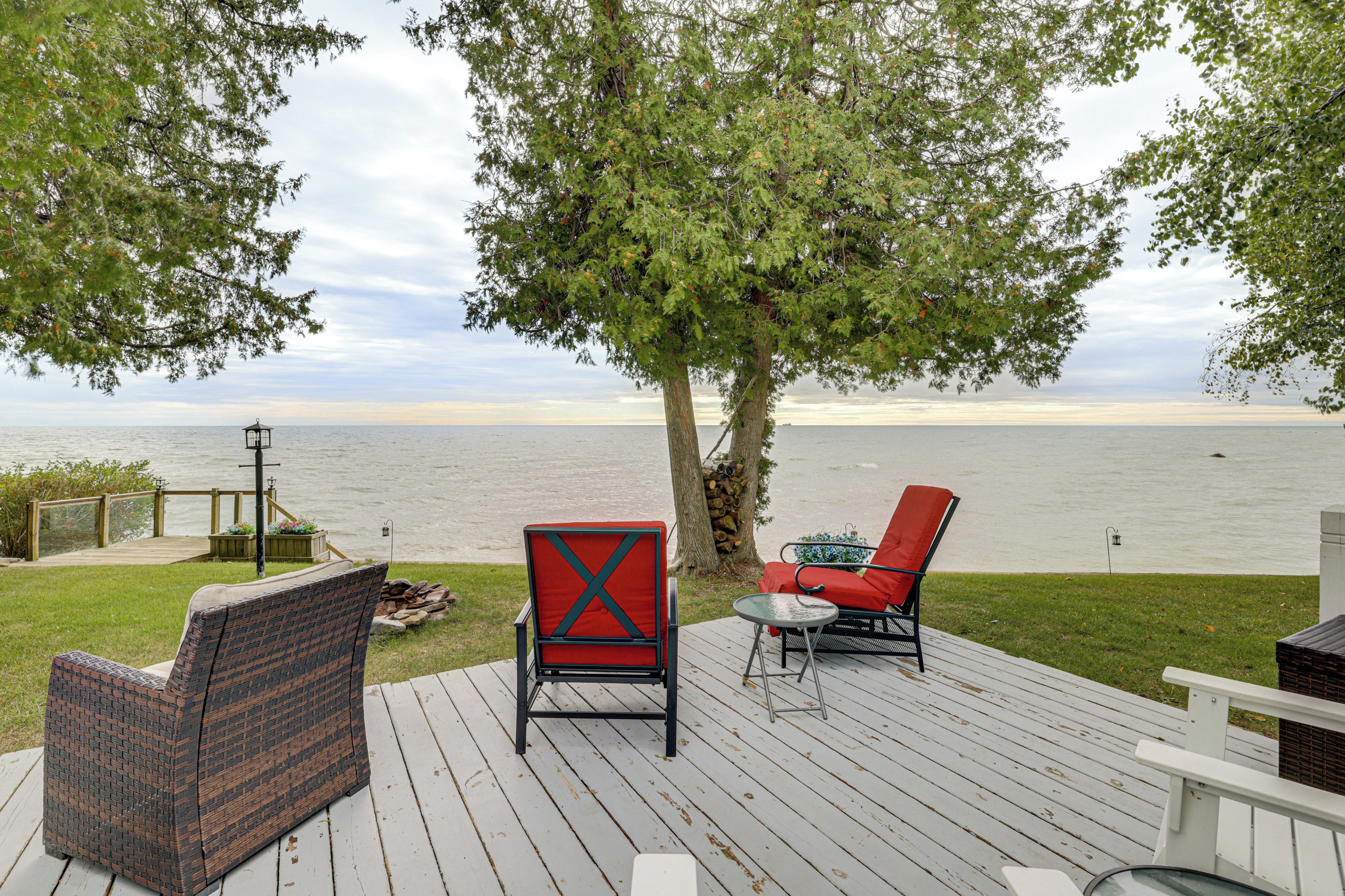 A deck with outdoor furniture, a view of the water, and a tree.