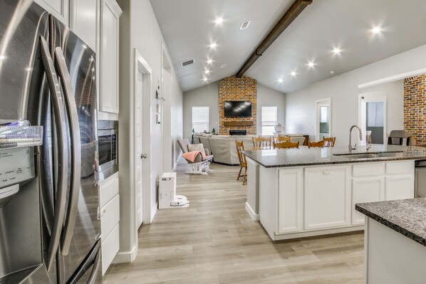 A modern kitchen with a large island, a built-in oven, and a refrigerator.