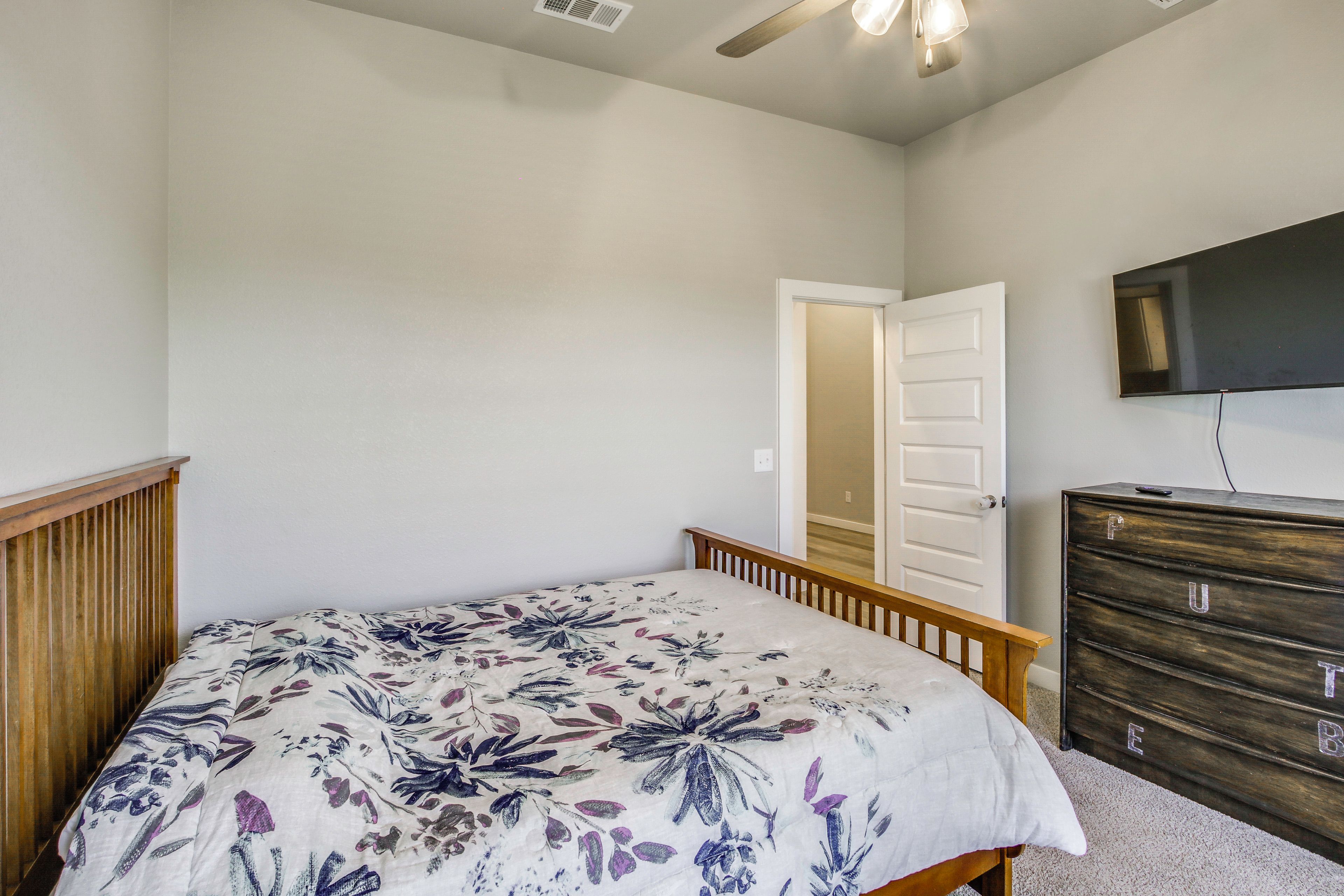 A bedroom with a bed, dresser, and a television on the wall.