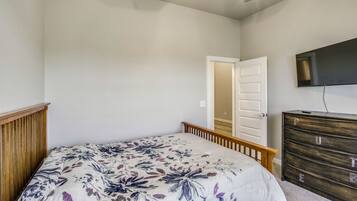A bedroom with a bed, dresser, and a television on the wall.