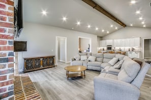 Un amplio salón con un sofá seccional gris grande, una mesa de centro de madera y una pared de ladrillo decorativa.