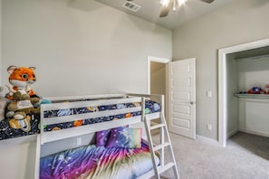 Ein Kinderstockbett mit Weltall-Thema, einer Leiter und einem Stofftier auf dem Bett.