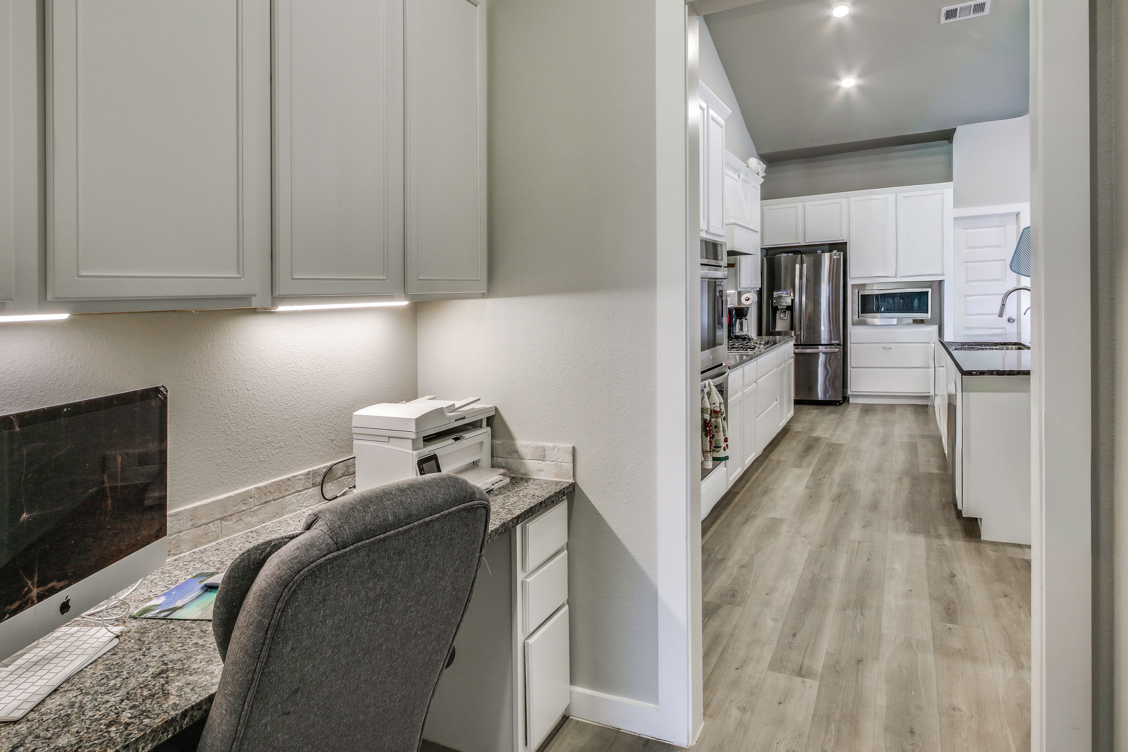 A modern kitchen with white cabinets, a granite countertop, and stainless steel appliances.