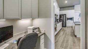 A modern kitchen with white cabinets, a granite countertop, and stainless steel appliances.