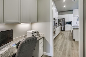 A modern kitchen with white cabinets, a granite countertop, and stainless steel appliances.