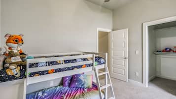 A child's bunk bed with space-themed bedding, a ladder, and a stuffed toy on the bed.