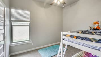 A child's bedroom with a bunk bed, a ceiling fan, a window with blinds, and a plush toy on the bed.