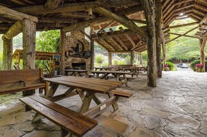 Ein offenes Holzpavillon mit Steinboden, Picknicktischen und Bänken.