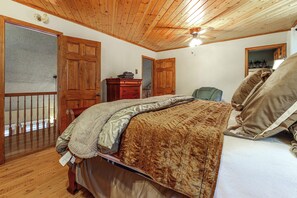 A bedroom with a wooden ceiling, a bed with multiple pillows, a dresser, and a door. - Hot Tub & Mtn Views: Wolf Laurel Home (Mars Hill)