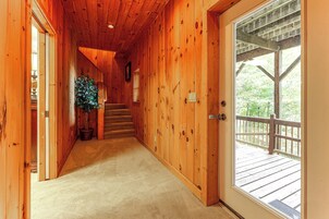 Ein Korridor mit Holzausbau führt zu einer Terrasse mit Geländer.