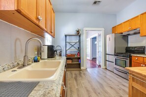 A kitchen with wooden cabinets, a stainless steel sink, a built-in oven, and a refrigerator. - Quaint North Campus Bungalow Minutes From Downtown (Austin)