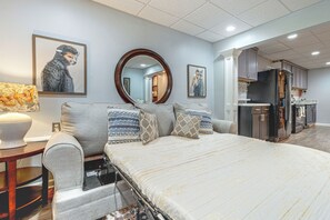 A bedroom with a bed, a bedside table, a mirror, and a view into the adjacent kitchen. - Wooded Extended Retreat: 15 Mi to Lake Lanier! (Cumming)