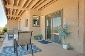 An outdoor patio with a covered seating area, a sliding glass door, and potted plants. - Poolside Fun + Zion Day Trips! Mtn-view Getaway (St. George)