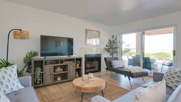Una sala de estar moderna con un televisor de pantalla plana, una chimenea y una zona de estar acogedora con sofá y sillones.