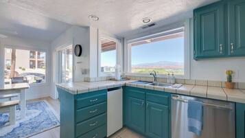 A kitchen with teal cabinets, a sink, and a window with a view of mountains.