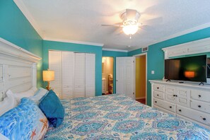 A bedroom with a bed, a dresser, a television, and a ceiling fan. - Unwind Poolside, Walk to Shore! Port Aransas Condo (Port Aransas)