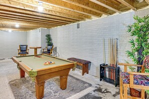 A pool table with chairs and a plant in a room with exposed wooden beams and brick walls. - Hot Tub, Game Room & Steps to Pond! Elkhart Escape (Elkhart)
