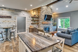 Una cocina moderna con una pared de acento de piedra, un comedor con mesa de madera y una sala de estar con sofá azul.