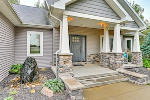 A house with a stone entryway, a front door, and a small garden with rocks and plants. - Hot Tub, Game Room & Steps to Pond! Elkhart Escape (Elkhart)
