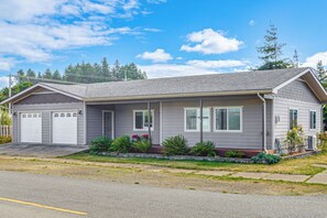 A single-story house with a garage, a front porch, and a small garden with various plants. - Holiday at Alsea Bay: 1 Block to the Bay! (Waldport)