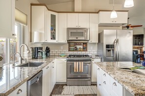 A modern kitchen with white cabinetry, stainless steel appliances, a granite countertop, and a built-in oven with a towel rack. - Holiday at Alsea Bay: 1 Block to the Bay! (Waldport)