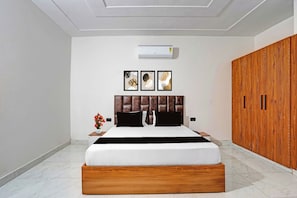 A bedroom with a bed, a wooden wardrobe, and three framed pictures on the wall.