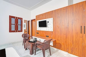 A modern room with a wooden wardrobe, a TV mounted on a marble wall, a dining table with chairs, and a coffee station. - Collection O NIT Kurukshetra Formerly (Thanesar)