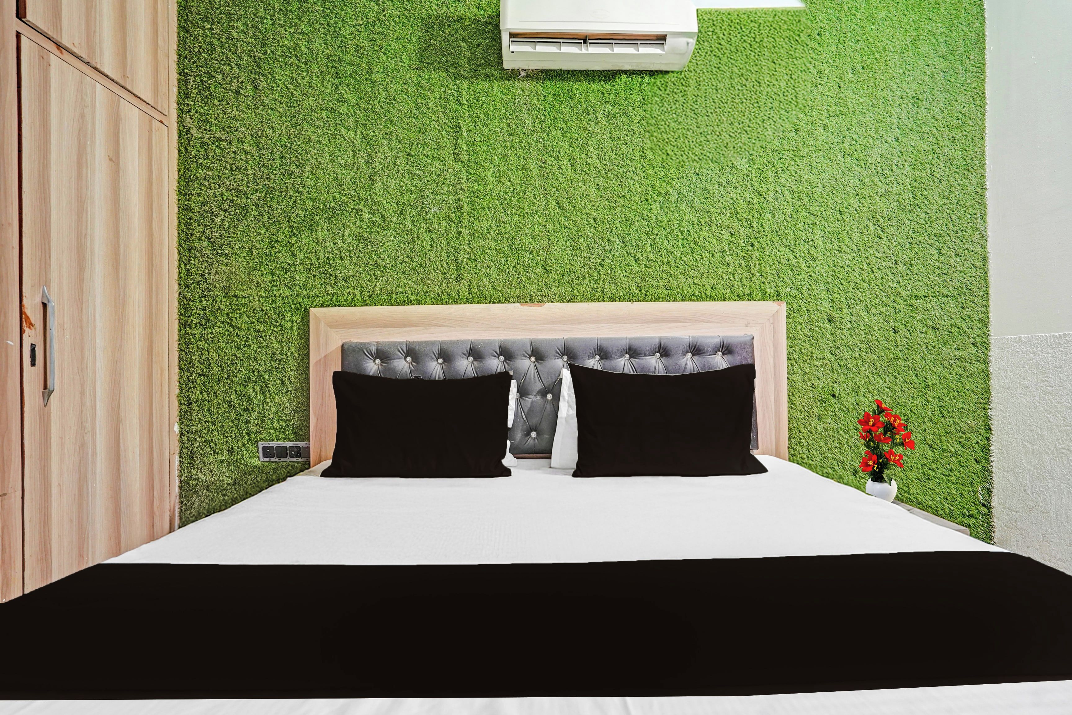 Un dormitorio con cama, cabecera, aire acondicionado de pared y una pequeña planta en maceta.
