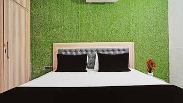 Un dormitorio con cama, cabecera, aire acondicionado de pared y una pequeña planta en maceta.