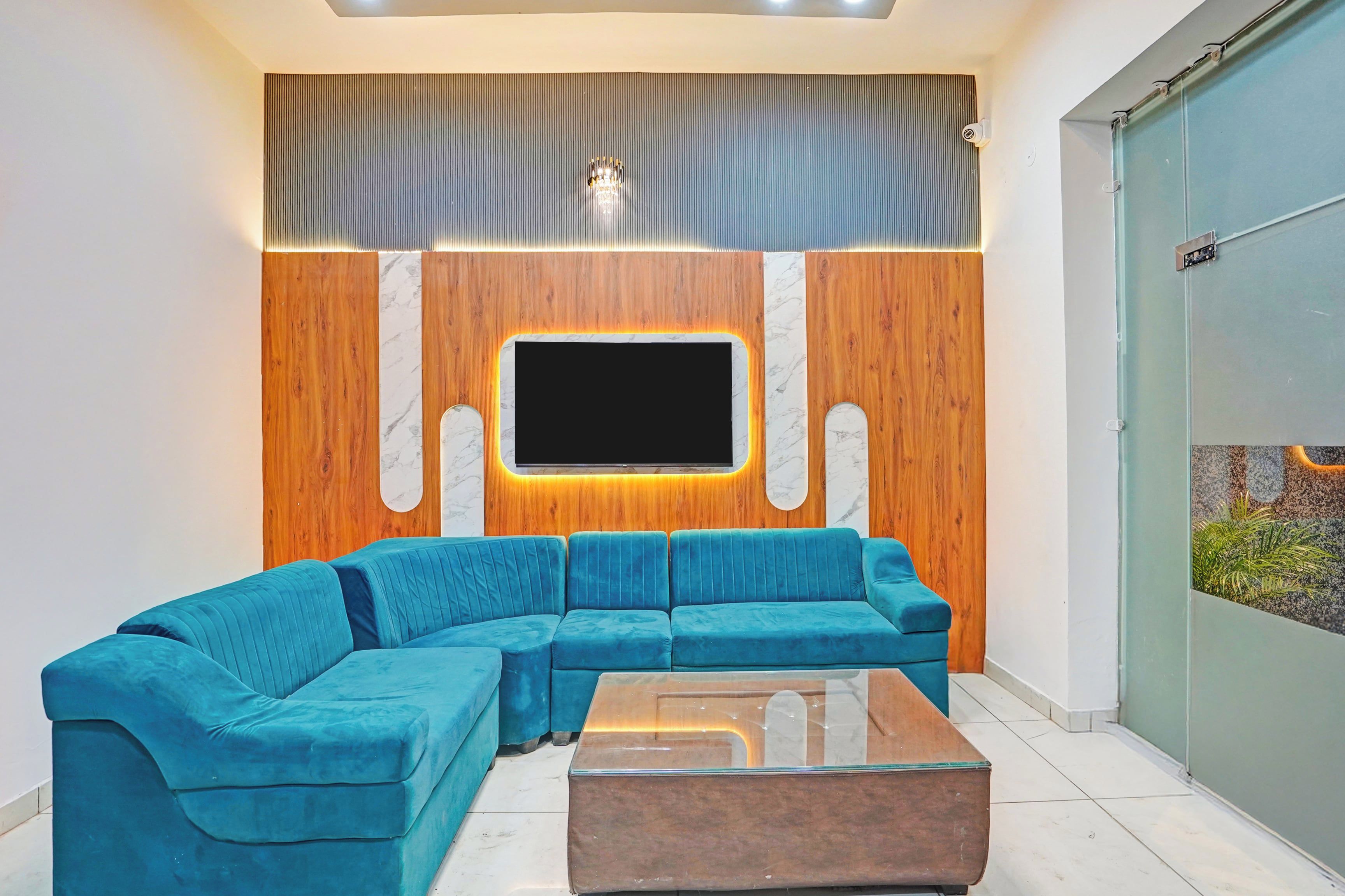 Sala de estar com sofá modular, mesa de centro, televisão de tela plana fixada em parede de madeira com detalhes em mármore, e porta de vidro deslizante que dá para uma varanda.