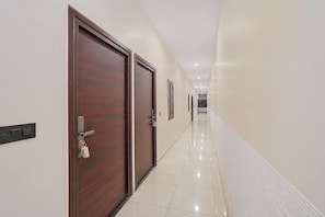 Un pasillo con dos puertas de madera, un interruptor de luz y un lector de tarjetas.