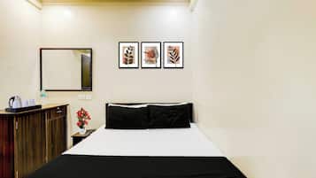 Habitación de hotel con una cama, un escritorio con espejo y tres cuadros en la pared.