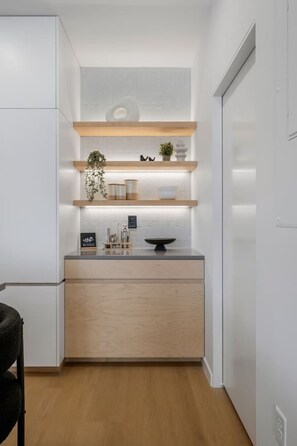 A modern kitchen with white cabinetry, wooden countertops, and built-in shelves. - New 3-Story Luxury Stay by City Park & Aggieville (Manhattan)