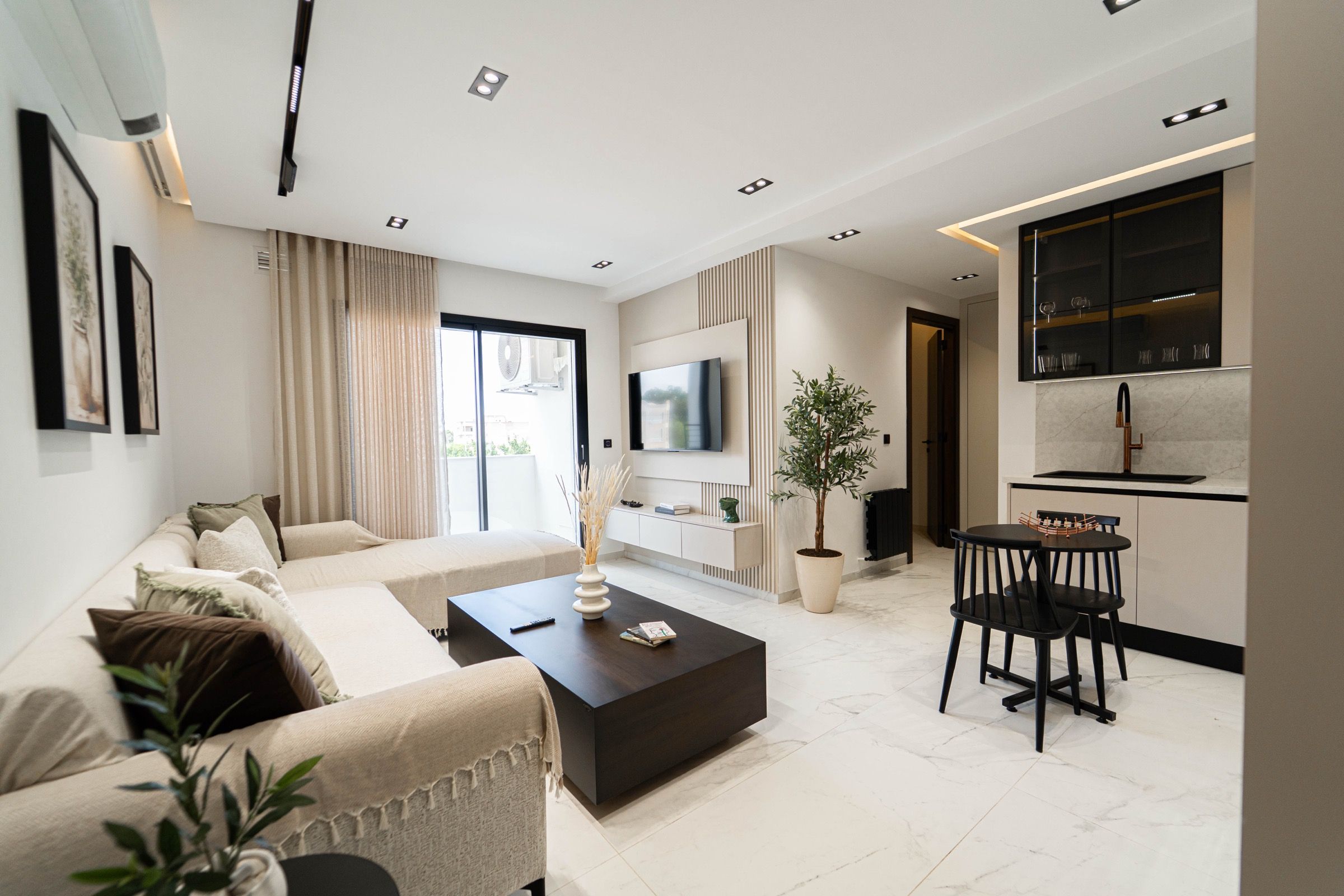 Un salon moderne avec un canapé, une table basse et un téléviseur. Il y a également un coin repas avec une table et des chaises.