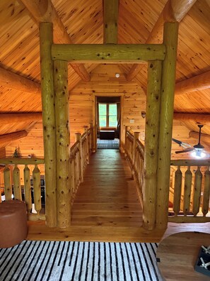 A wooden interior with a central hallway leading to a door, wooden railings, and a ceiling fan. - Secluded Adirondack Lodge, Near Whiteface, Private trails (Jay)