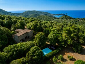 A stone villa with a swimming pool surrounded by dense greenery and a view of the sea. - Villa Relais Il Termine: Historic villa on a 70,000 m² estate with ocean views (Rio Marina)