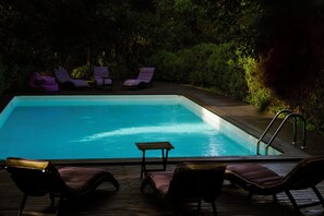 A rectangular swimming pool with a wooden deck surrounding it. There are lounge chairs and a small table on the deck. - Villa Relais Il Termine: Historic villa on a 70,000 m² estate with ocean views (Rio Marina)