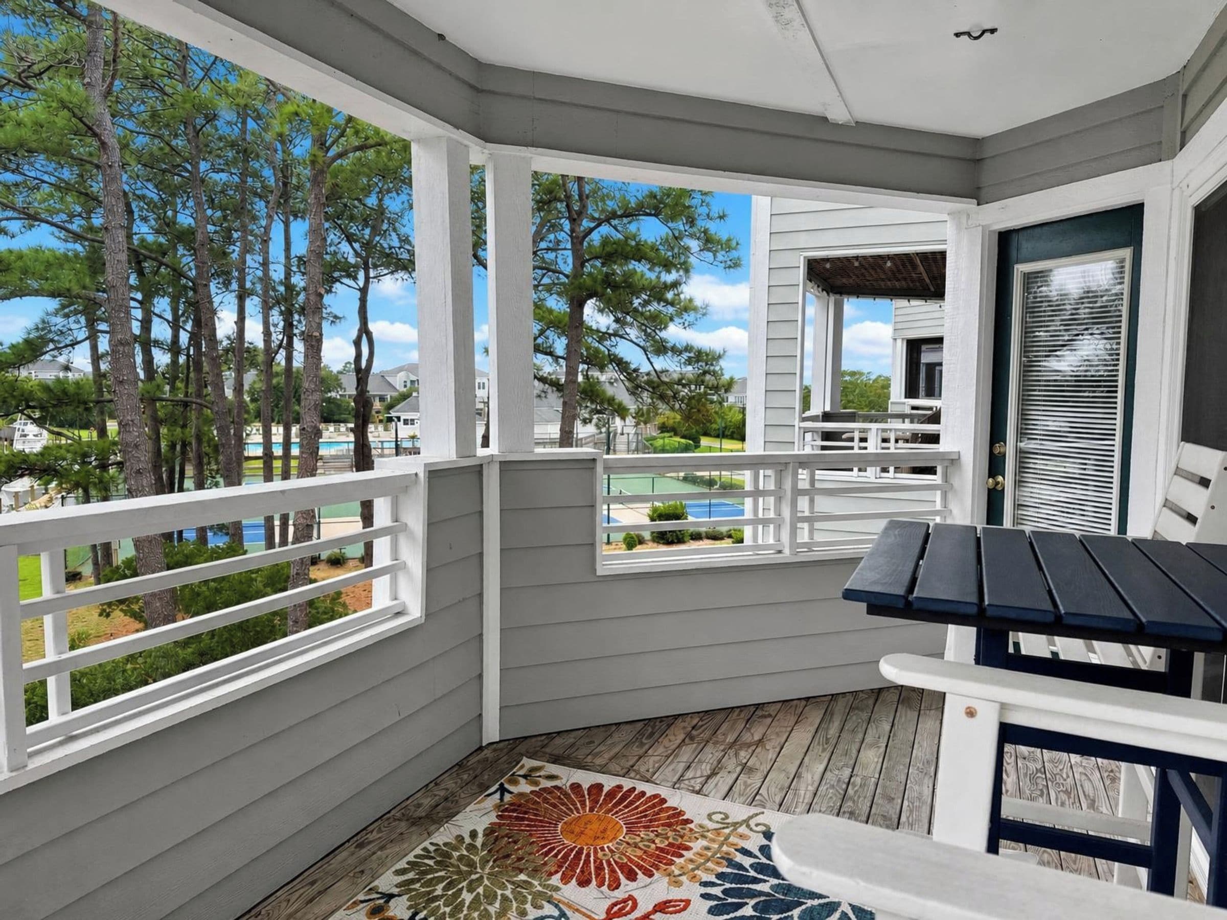 A covered porch with a view of a pool and trees.
