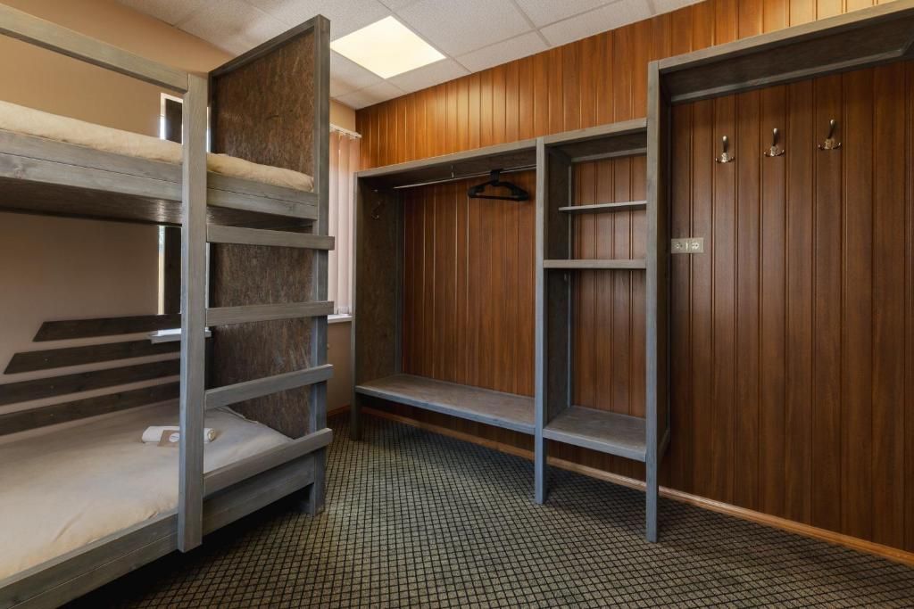 Une chambre avec un lit superposé, une armoire en bois et une étagère en métal.
