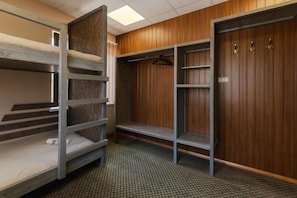 A bunk bed room with a wooden wardrobe and a metal shelf unit.