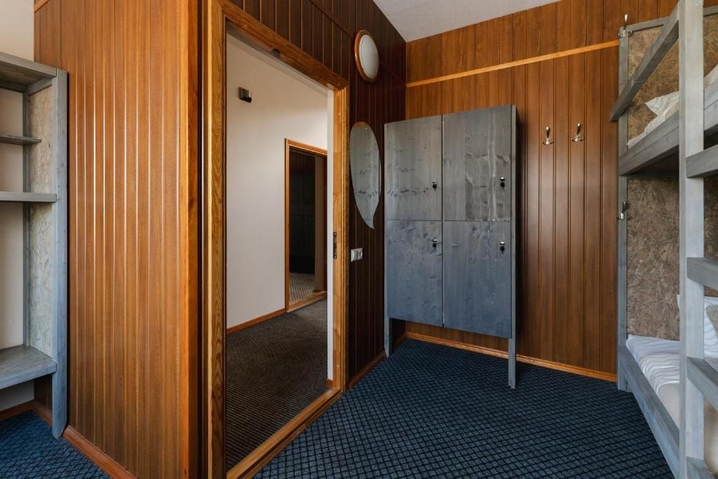 Una habitación con un armario de madera, una cama con colchón blanco y un suelo de diseño azulado.