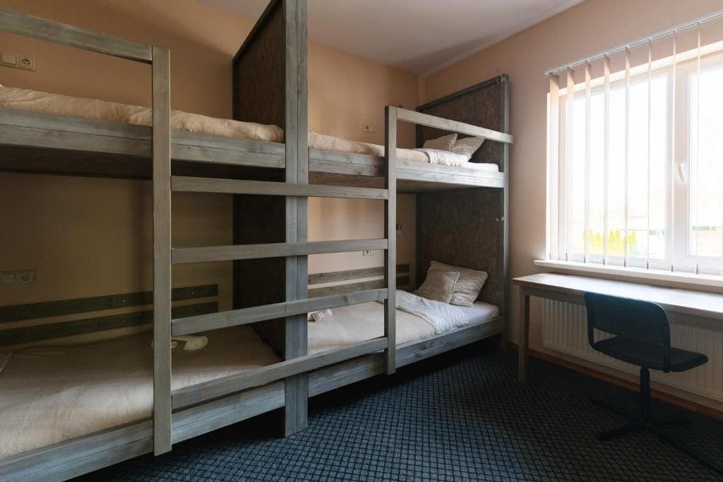 Un dormitorio con literas, un radiador y una ventana con persianas.