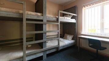 Un dormitorio con literas, un radiador y una ventana con persianas.